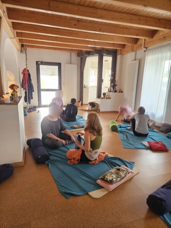 Teilnehmende sitzen im Gespräch auf türkisen Decken im Studio