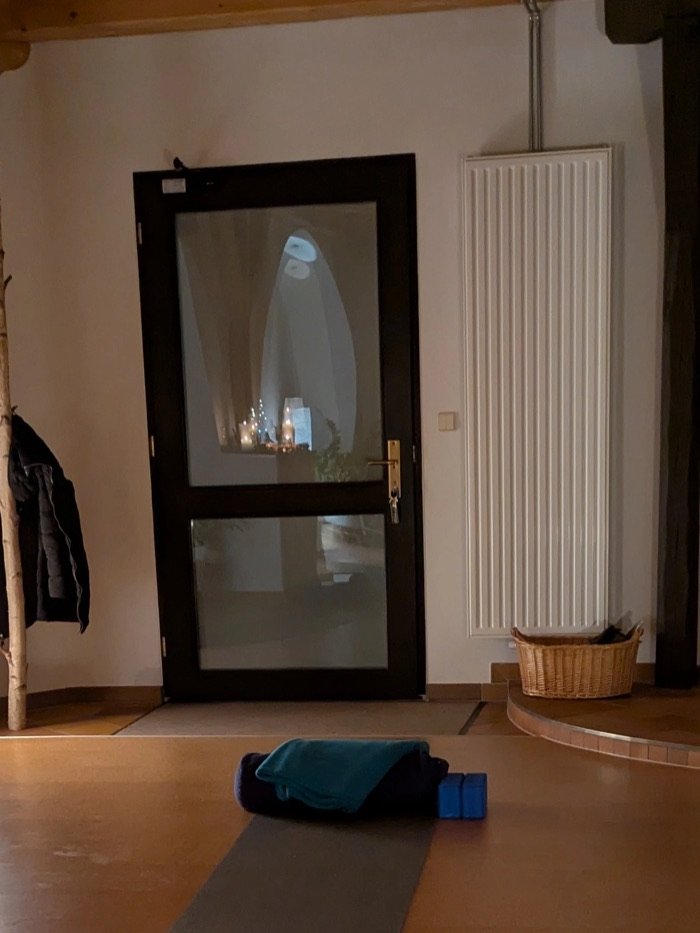 Dunkle Glastür mit Spiegelung von Kerzenlicht, daneben ein Heizkörper und ein Weidenkorb